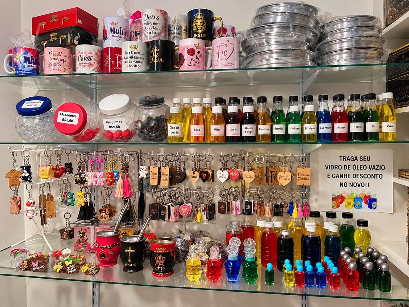 Prateleiras com óleos de unção, canecas personalizadas e chaveiros cristãos
